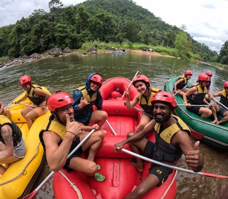 Un grupo de WeRoad en balsas inflables posa para una foto en un río, con cascos rojos y chalecos salvavidas, y una colina boscosa de fondo.