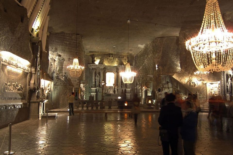 L'interno di una grande cappella sotterranea scavata nella roccia, illuminata da diversi lampadari di cristallo ornati.