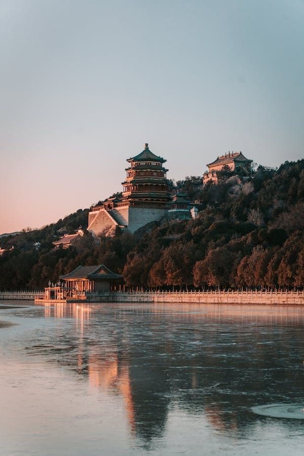 Una pagoda tradizionale su una collina boscosa sopra un lago ghiacciato al tramonto