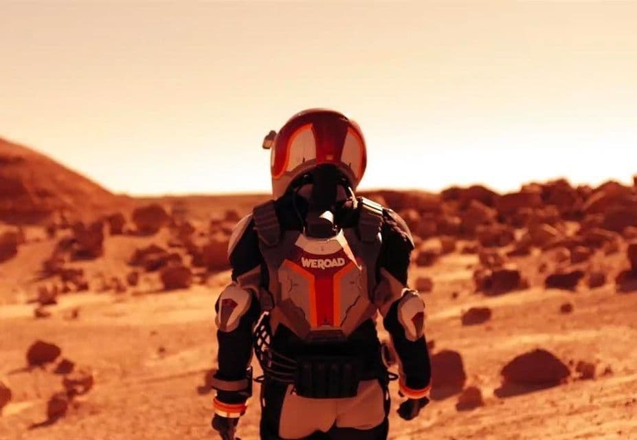 Un astronauta che indossa una tuta spaziale a marchio WeRoad si erge su un terreno desertico roccioso e rosso.