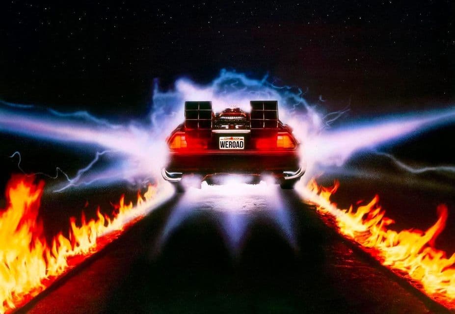 Una DeLorean con targa 'WEROAD' lascia tracce di pneumatici infuocate e scie di energia blu su una strada sotto un cielo stellato.