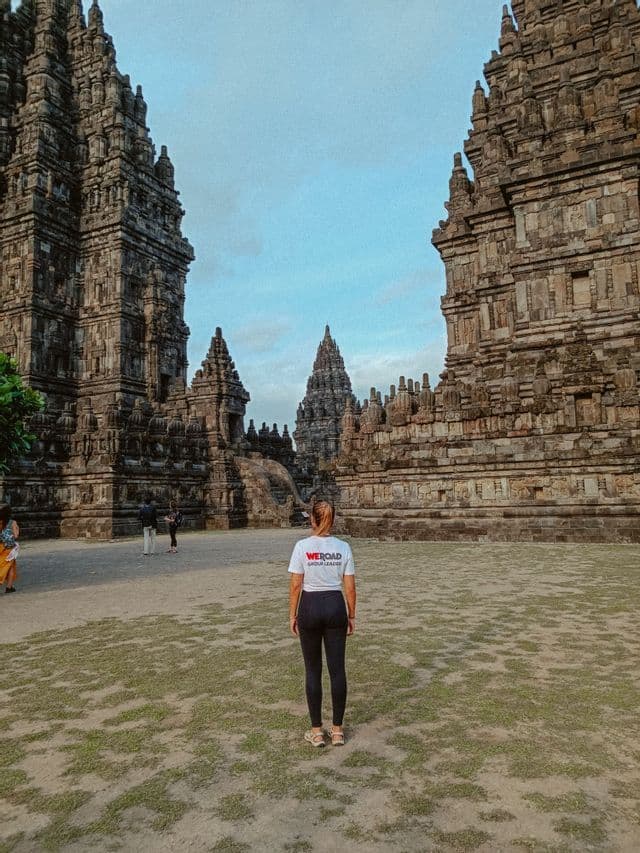 Una mujer con una camiseta de WeRoad Group Leader está de espaldas a la cámara, mirando un antiguo complejo de templos de piedra.