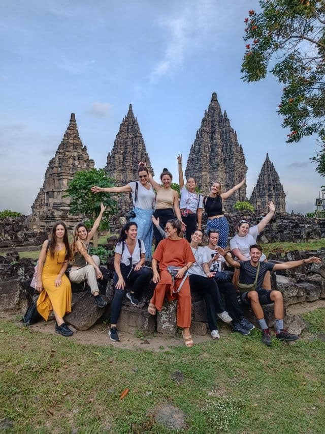 Un viaje en grupo de WeRoad posando juntos para una foto, sentados sobre ruinas de piedra frente a templos antiguos