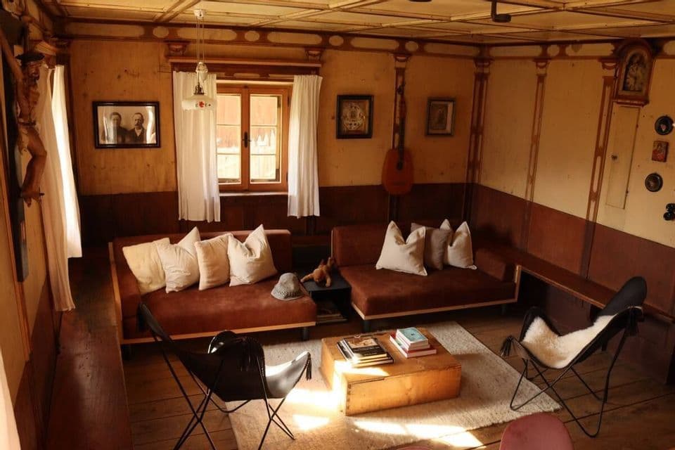 L'interno di un salotto rustico con rivestimento in legno, divani marroni, un tavolino da caffè e poltrone a farfalla.