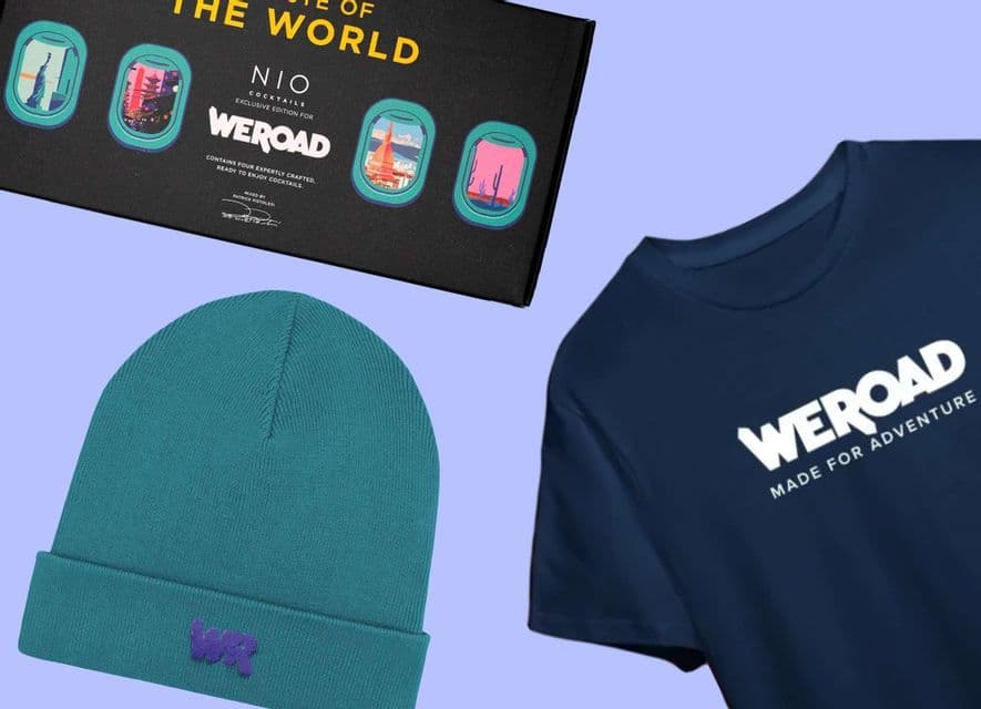 Una composizione flat lay di articoli brandizzati WeRoad, inclusa una t-shirt blu scuro, un berretto verde acqua e una scatola esclusiva di NIO Cocktails.
