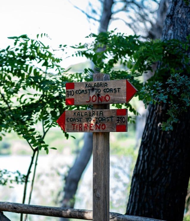Un segnavia in legno con frecce rosse per il percorso Kalabria Coast to Coast, che indica Jonio e Tirreno.