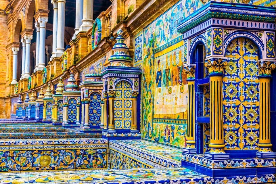 Dettaglio di intricate piastrelle azulejo in ceramica blu e gialle che rivestono panchine e pilastri di un edificio.