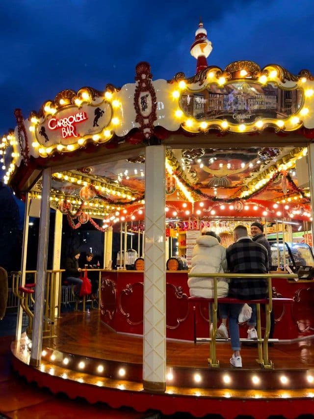 Un grupo WeRoad conversando en un bar dentro de un carrusel iluminado por la noche.