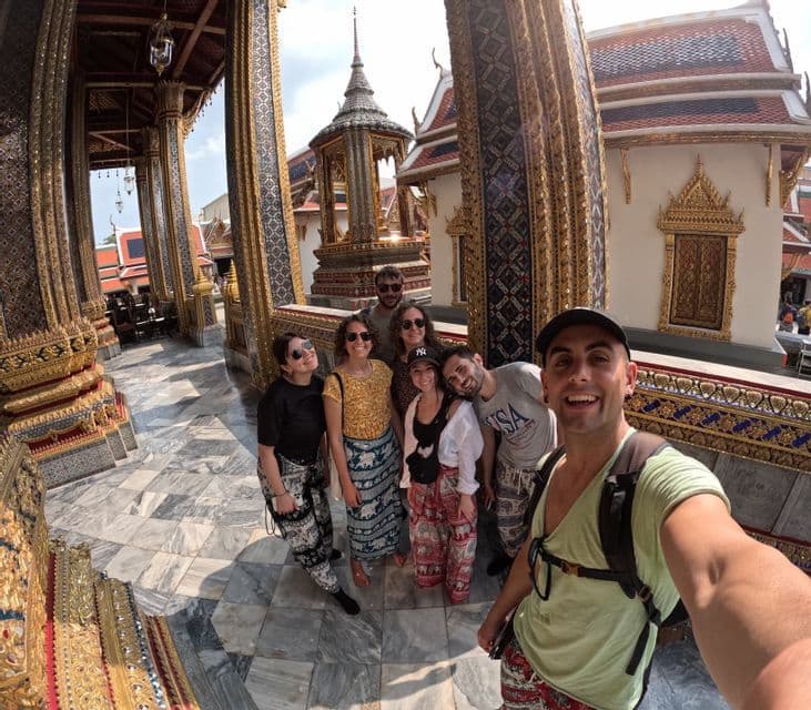 Eine WeRoad-Gruppe macht ein Selfie in einem verzierten Tempel mit goldenen Säulen und einem Marmorboden.
