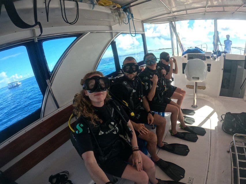 A WeRoad group trip in full scuba gear sitting inside a boat, preparing to go diving in the sea.