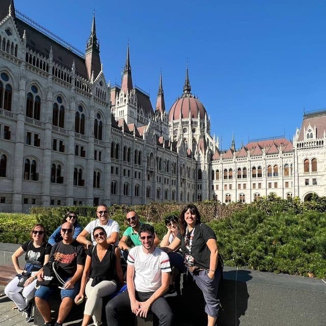 Eine WeRoad-Gruppe posiert gemeinsam für ein Foto auf einer Bank vor einem großen, verzierten Regierungsgebäude.