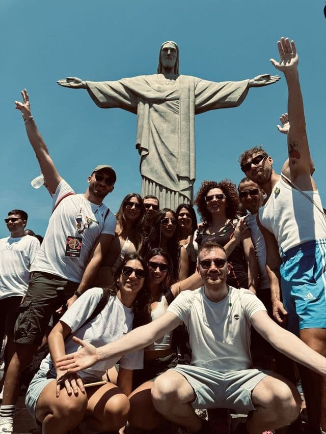 Eine WeRoad-Gruppe posiert für ein Gruppenfoto vor der Christusstatue unter strahlend blauem Himmel.