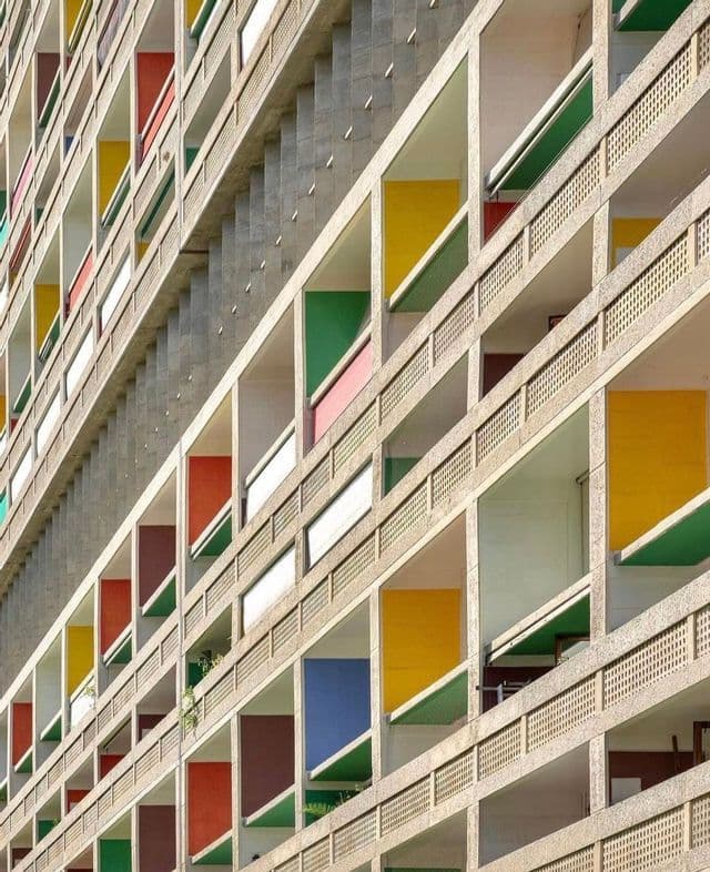 La facciata geometrica di un edificio in cemento con un motivo di balconi incassati e pareti dai colori vivaci