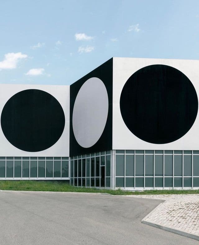 La facciata di un edificio moderno caratterizzata da un audace motivo di grandi cerchi bianchi e neri sopra una fila di finestre.