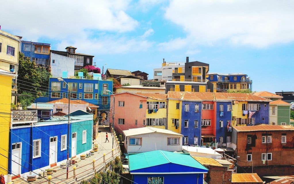 Edificios de colores vivos se apiñan en una ladera bajo un cielo azul.