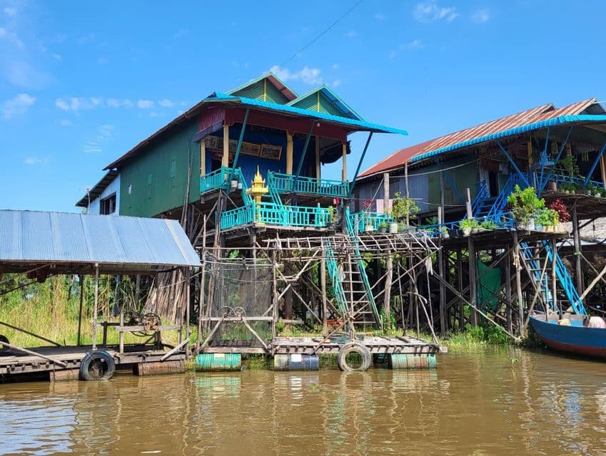 Casas de palafitos coloridas con balcones y techos de chapa se alzan sobre un río lodoso bajo un cielo azul.