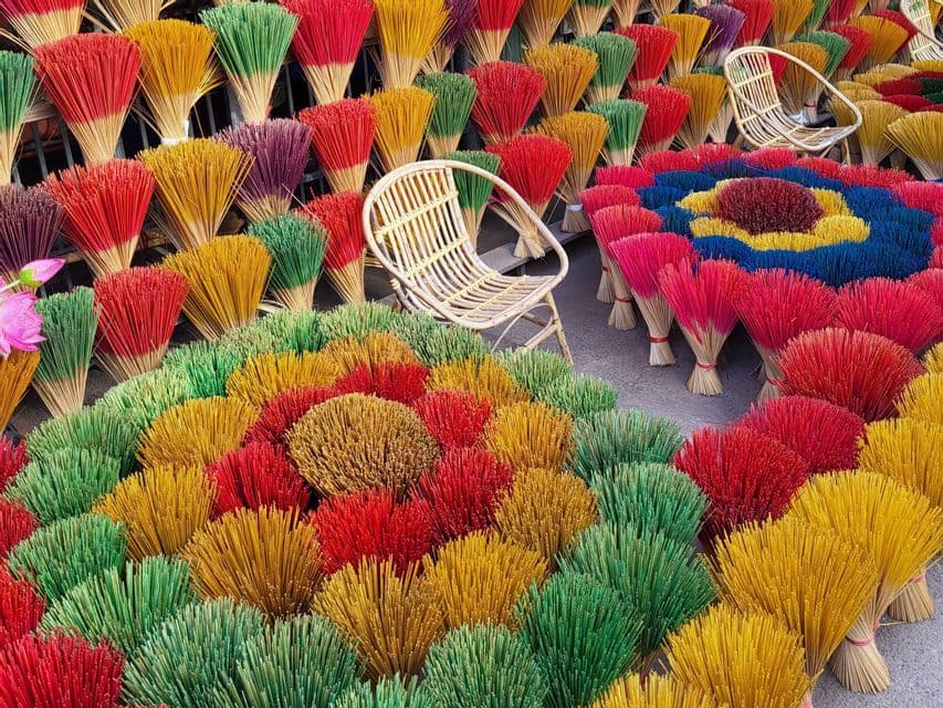 Una gran exhibición de manojos de varitas de incienso coloridos dispuestos en forma de abanico, con dos pequeñas sillas de mimbre en el centro.