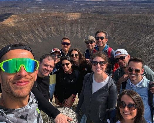 Un gruppo WeRoad si scatta un selfie sul bordo di un grande cratere vulcanico.