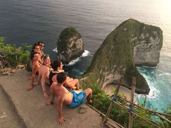 Eine WeRoad-Gruppenreise am Rande einer hohen Klippe, mit Blick auf eine dramatische Küstenlinie und grün bewachsene Felsformationen.