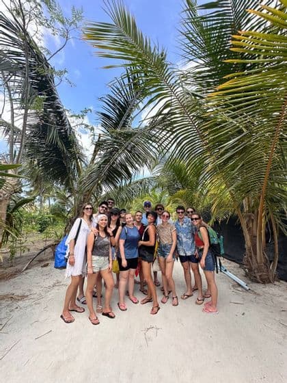 Un gruppo WeRoad in viaggio posa per una foto su un sentiero sabbioso circondato da alte palme.