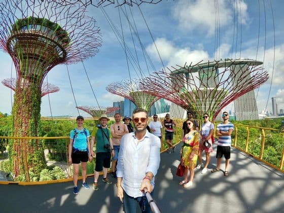 Un gruppo WeRoad si scatta un selfie su una passerella sospesa tra futuristici Supertrees con lo skyline della città sullo sfondo.