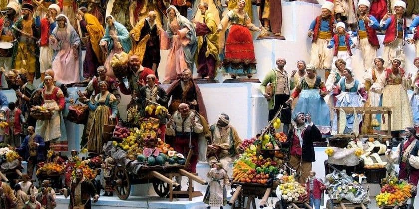 Una collezione affollata di statuine dettagliate in abiti tradizionali che raffigurano un vivace mercato con carretti di frutta.