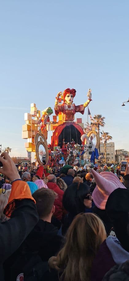 Un grande carro di carnevale con la Regina di Cuori che si scatta un selfie è ammirato da una vasta folla di spettatori.