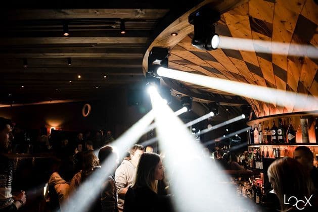 Viaggio di gruppo WeRoad che socializza in una discoteca buia, illuminata da potenti faretti provenienti da un soffitto in legno.