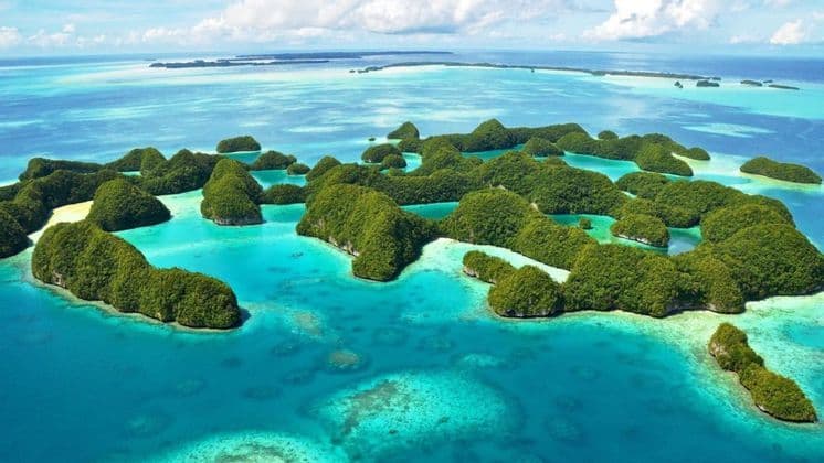 Una vista aerea di un arcipelago con molte piccole isole verdi e lussureggianti sparse su un oceano turchese e blu.