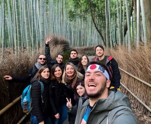 A WeRoad group trip smiles for a selfie on a path through a dense green bamboo forest.