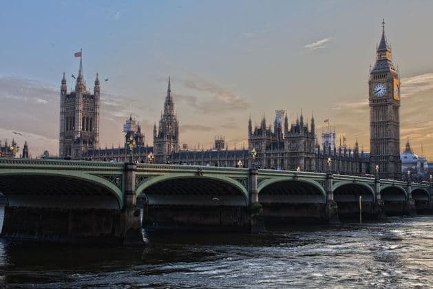 Una veduta del Palazzo del Parlamento e della torre dell'orologio del Big Ben dal Tamigi, con il Ponte di Westminster in primo piano al crepuscolo.