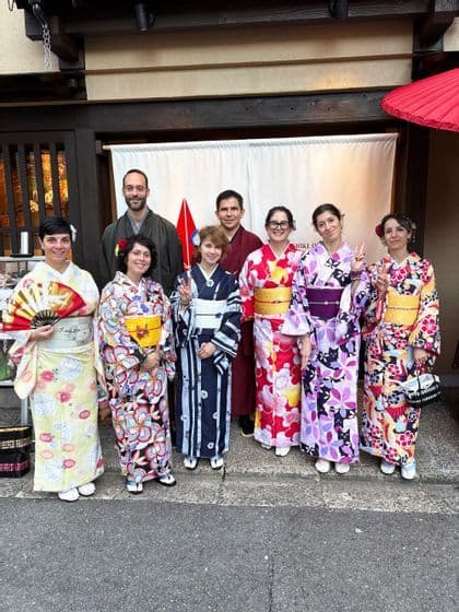 Un viaje en grupo de WeRoad con ocho personas posando juntas mientras visten coloridos kimonos tradicionales frente a un edificio.