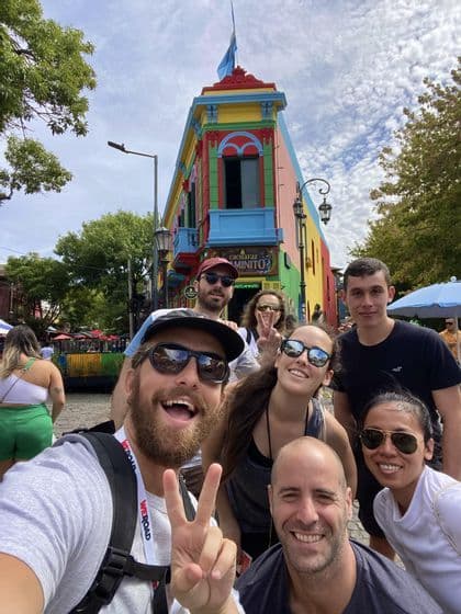 A WeRoad group trip smiling and taking a selfie on a city street in front of a multi-colored building.