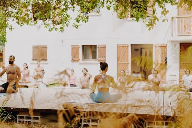 Un viaggio di gruppo WeRoad con una sessione di yoga all'aperto su una pedana di legno di fronte a una casa.