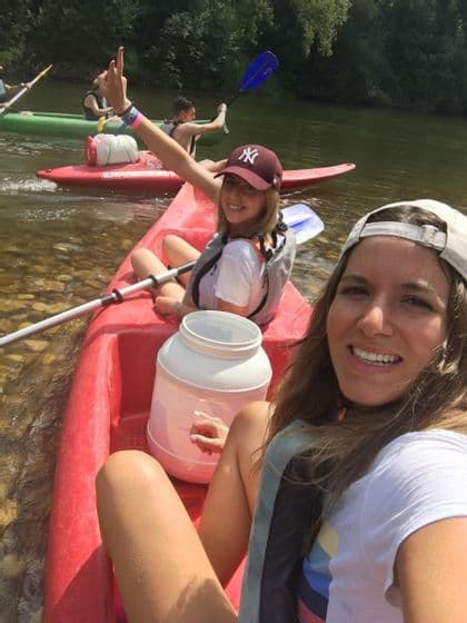Dos mujeres en un viaje grupal de WeRoad se toman una selfie mientras hacen kayak en un kayak rojo en un río.