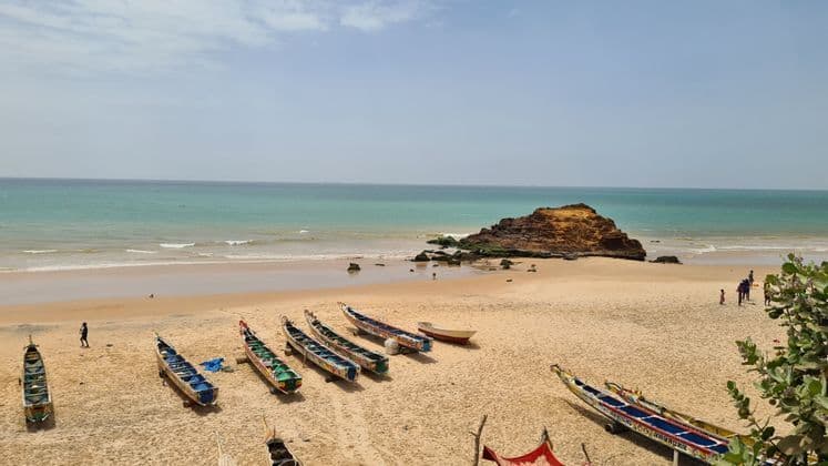 Erhöhter Blick auf farbenfrohe, traditionelle Boote an einem Sandstrand am türkisfarbenen Meer.