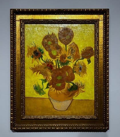 Vincent van Goghs Gemälde 'Sonnenblumen' in einem verzierten, vergoldeten Rahmen an einer Galeriewand.