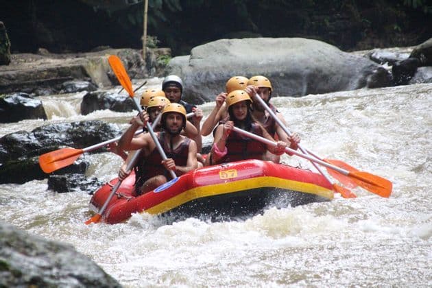 Un viaggio di gruppo WeRoad con caschi e giubbotti di salvataggio mentre fanno rafting su un gommone rosso in un fiume impetuoso.