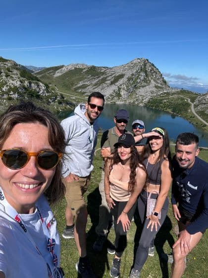 Un grupo de WeRoad sonríe para una selfie frente a un lago de montaña en un día soleado.