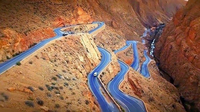 Una vista aerea di una strada tortuosa con tornanti che attraversa un vasto canyon roccioso.