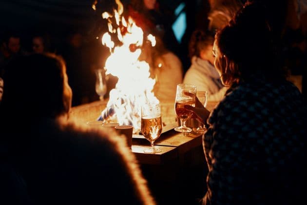 Eine WeRoad-Gruppe versammelt sich nachts am Lagerfeuer, mit Biergläsern auf dem Tisch.
