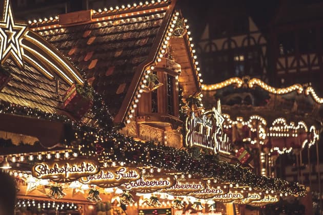 Un puesto de chalet de madera en un mercado nocturno festivo, iluminado por cálidas luces de guirnalda, festones y una gran estrella.