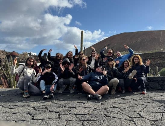 Un grupo de WeRoad posando para una foto en un patio de piedra en un paisaje rocoso con una colina de fondo.