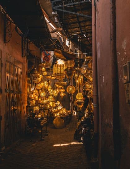Numerosos faroles metálicos ornamentados e iluminados cuelgan en un estrecho y oscuro callejón de mercado.