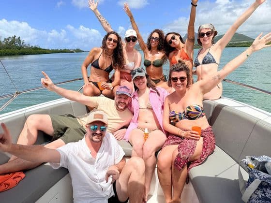 Un groupe WeRoad d'hommes et de femmes en maillot de bain souriant et posant ensemble à l'arrière d'un bateau sur l'eau.