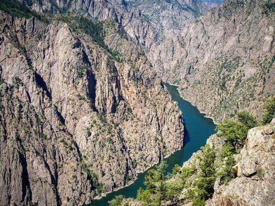 A high-angle view of a river winding through a steep, rocky canyon with sparse green vegetation.