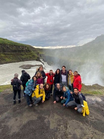 Un voyage de groupe WeRoad posant pour une photo sur une falaise dominant une puissante cascade dévalant dans un canyon.