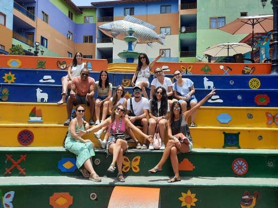 Un groupe WeRoad pose pour une photo sur un large escalier aux couleurs vives, décoré de symboles.