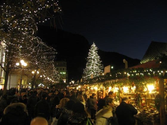 Un vivace mercatino di Natale di notte, con una folla di persone, bancarelle illuminate e alberi decorati con lucine.