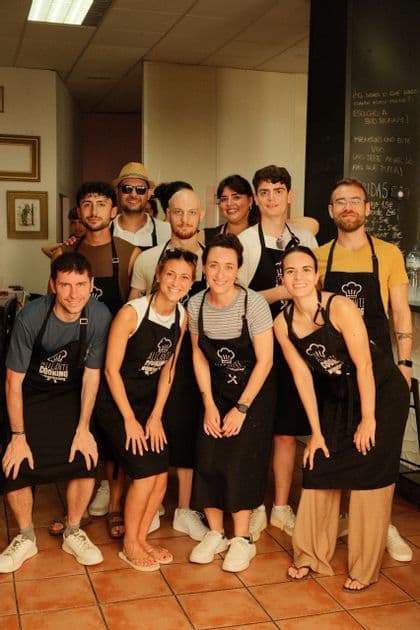 Un gruppo WeRoad in posa per una foto con grembiuli neri abbinati durante una lezione di cucina.
